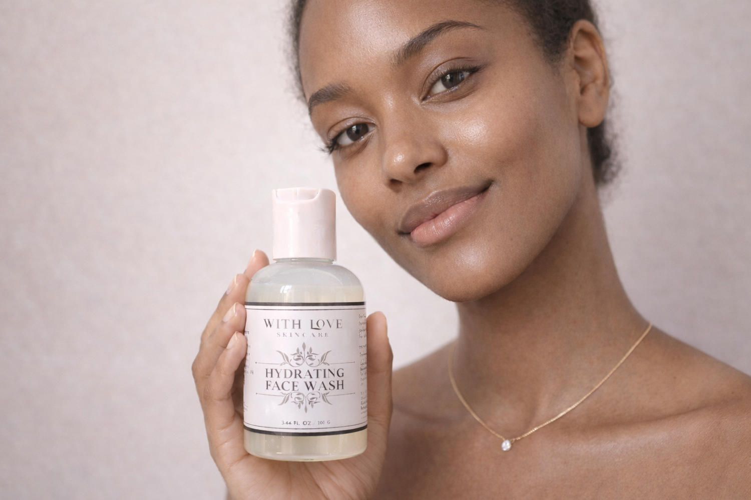 Woman holding a bottle of 'With Love' hydrating face wash against a plain background